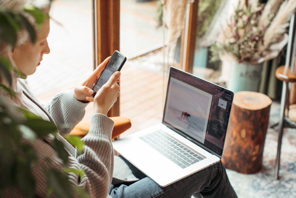 Young woman working remotely on a laptop in a cosy indoor space with natural light