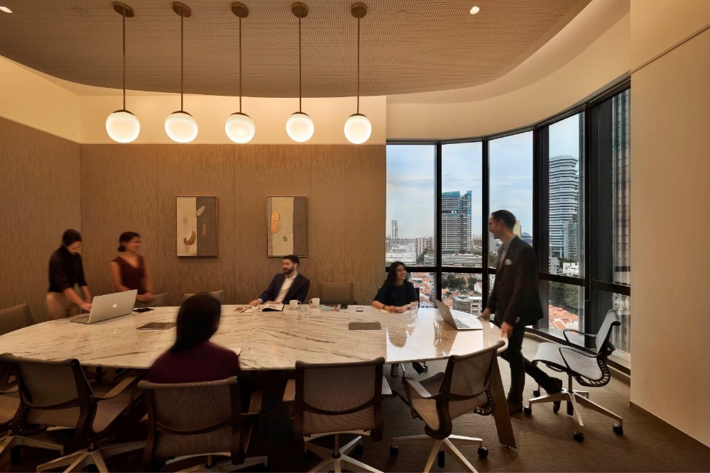 A group of professionals having a meeting in a modern, well-lit boardroom with a large window overlooking the city.