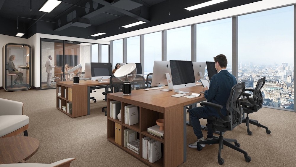 A man works at a desktop in a shared office space.